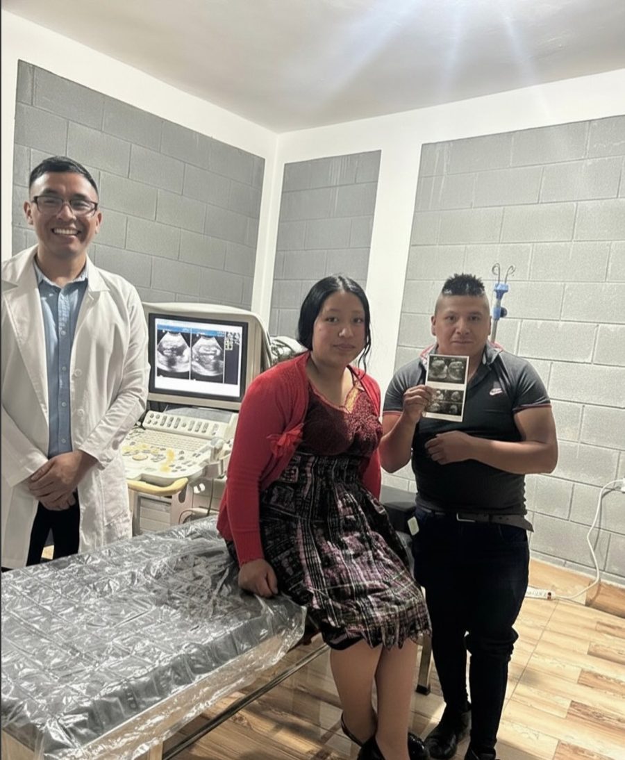 Dr. Eliseo Pelico stands beside the clinic’s ultrasound machine with a young couple holding an ultrasound printout.