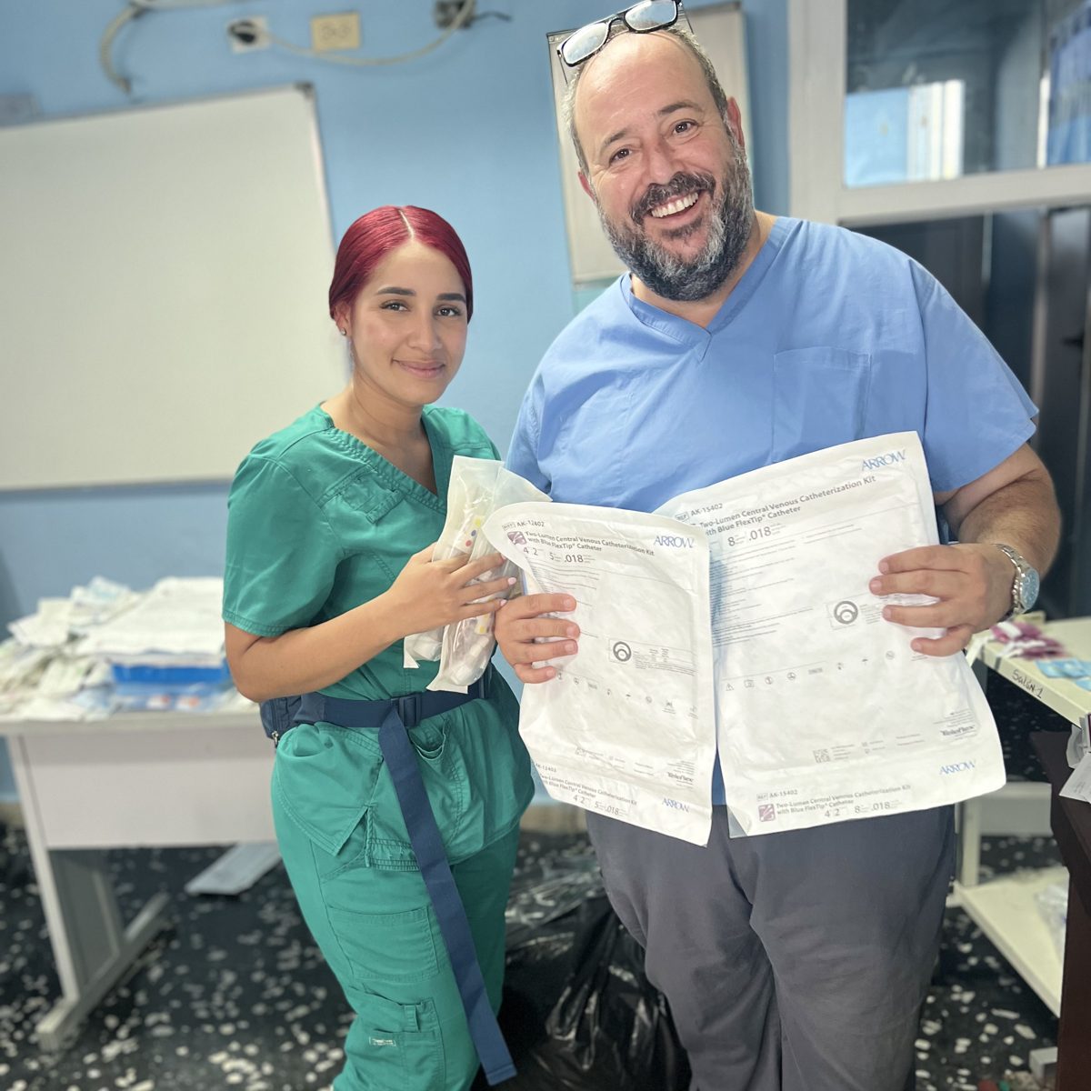 Two clinicians smile while holding signed delivery paperwork in a clinic.