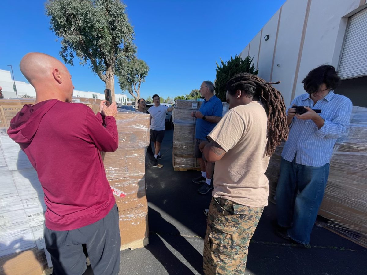 Volunteers photograph and scan wrapped pallets of supplies.